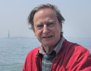 John Crook in red jacket, with statue of liberty in the far distance behind him