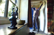 Statue of Buddha on window ledge with meditator behind