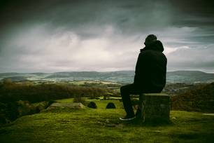 Person sitting on stone block overlooking landscape