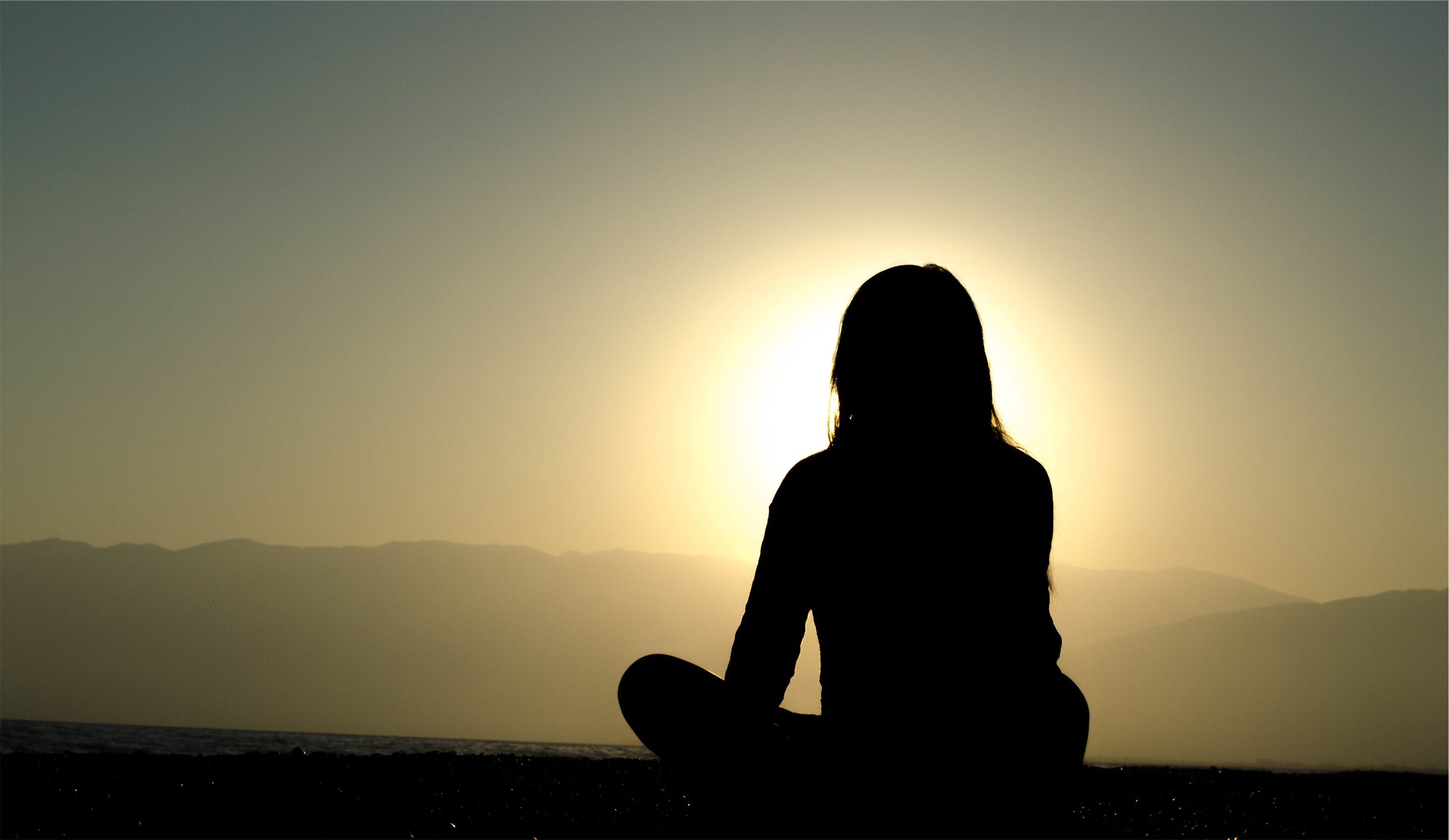 Person sitting cross-legged overlookinglandscape